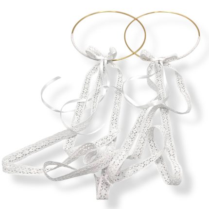Two gold wedding rings tied with white lace ribbons on a white background.