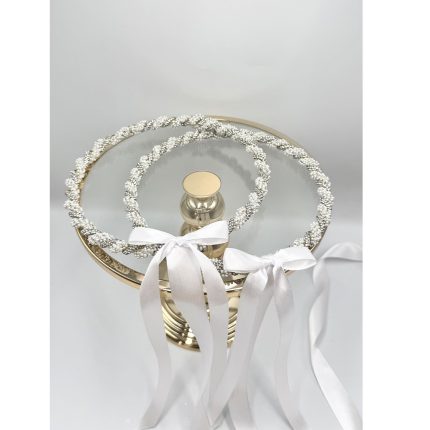 Two silver beaded halos with white satin ribbons draped over a gold pedestal mirror, a wedding decorative centerpiece.