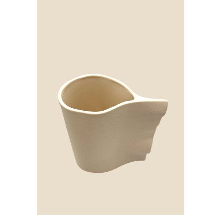 Cream-colored ceramic pitcher with a rounded spout, set against a pale beige background.