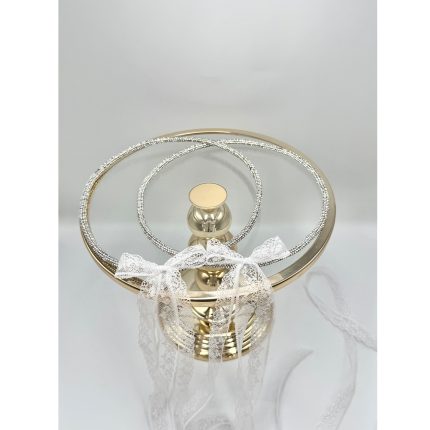 Gold pedestal glass cake stand with crystal ring decorations and white lace ribbon tied in a bow.