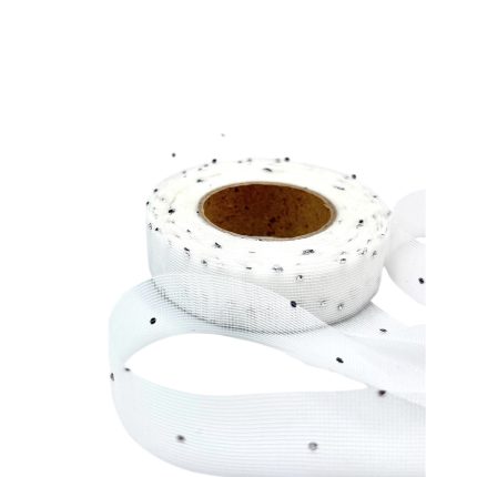 White decorative ribbon roll with small black specks scattered on the surface, partially unwound