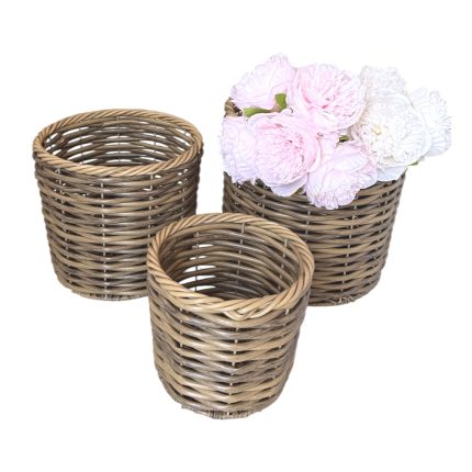 Three woven wicker baskets of different sizes, with pale pink and white peonies resting in the largest one.