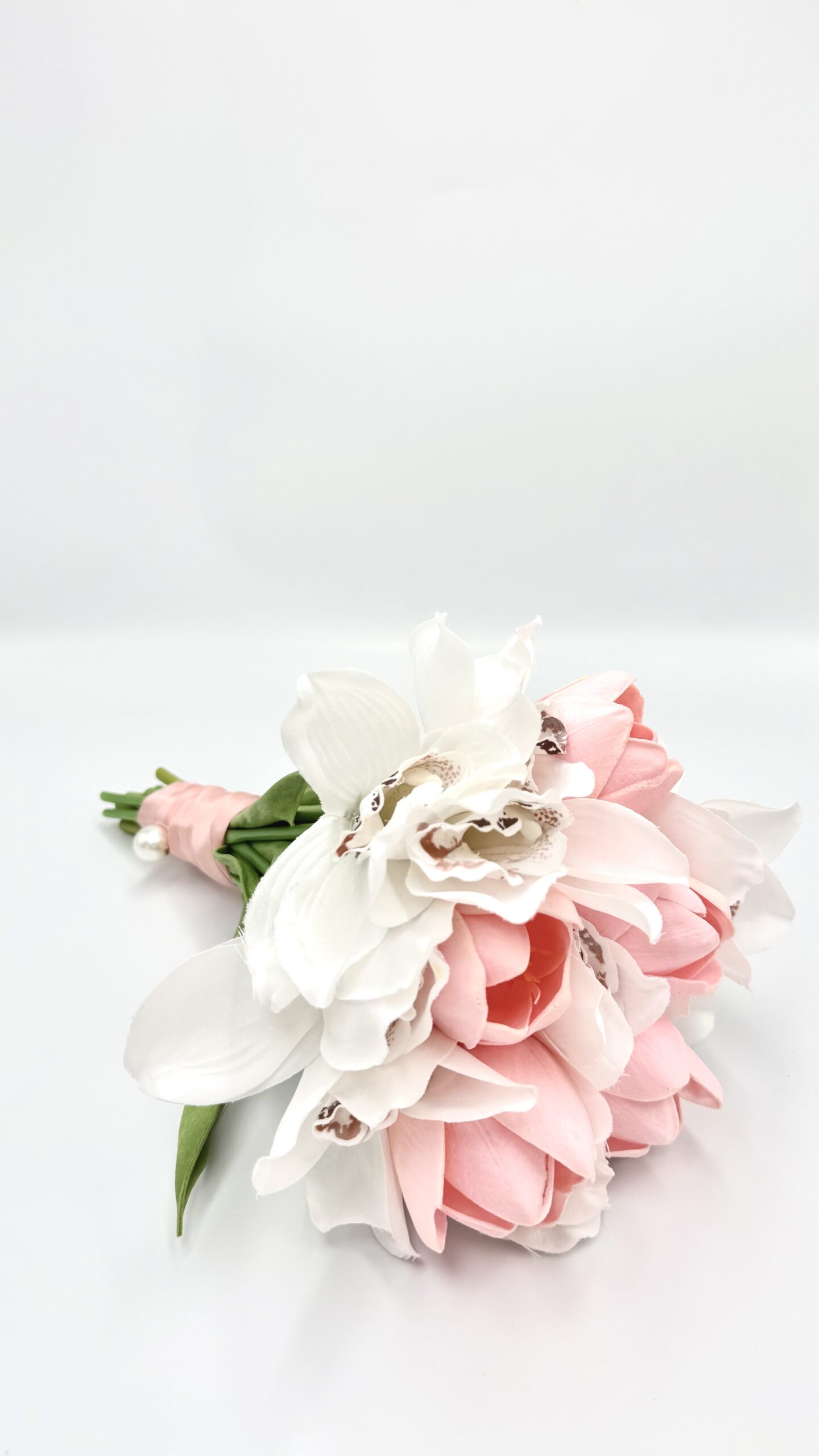 502C4E19-560D-D6C0-2388-019C9A4B2B0F_2-scaled1 | La Vie en Rose Pastel pink and white bouquet of flowers with green stems wrapped in pink ribbon on a white surface.
