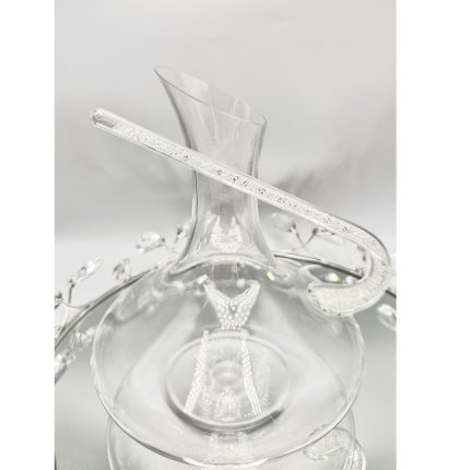 Clear glass vase with a crystal bracelet draped across its neck on a reflective surface.