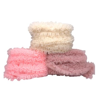 Three rolls of pastel ruffled fabric trim in cream, pink, and blush.