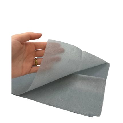 Hand with a gold ring peeling back a light gray sheet of paper.