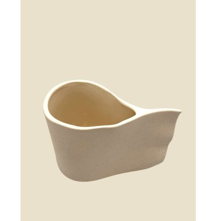 Cream-colored ceramic creamer pitcher with a curved spout, viewed from the side, empty inside.