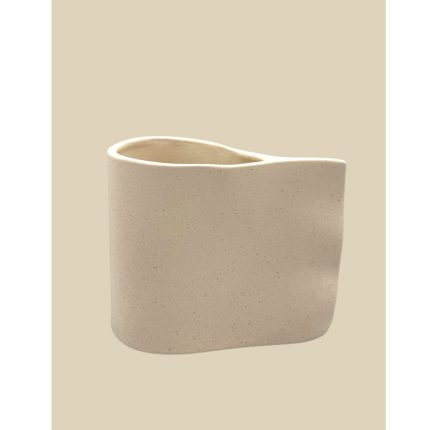 Beige speckled ceramic cup with a gently curved, uneven rim against a light tan background.