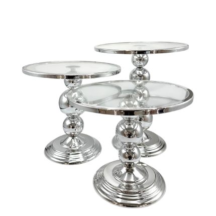 Set of three chrome pedestal tables with glass tops in varying heights, forming a nesting arrangement in a modern style.
