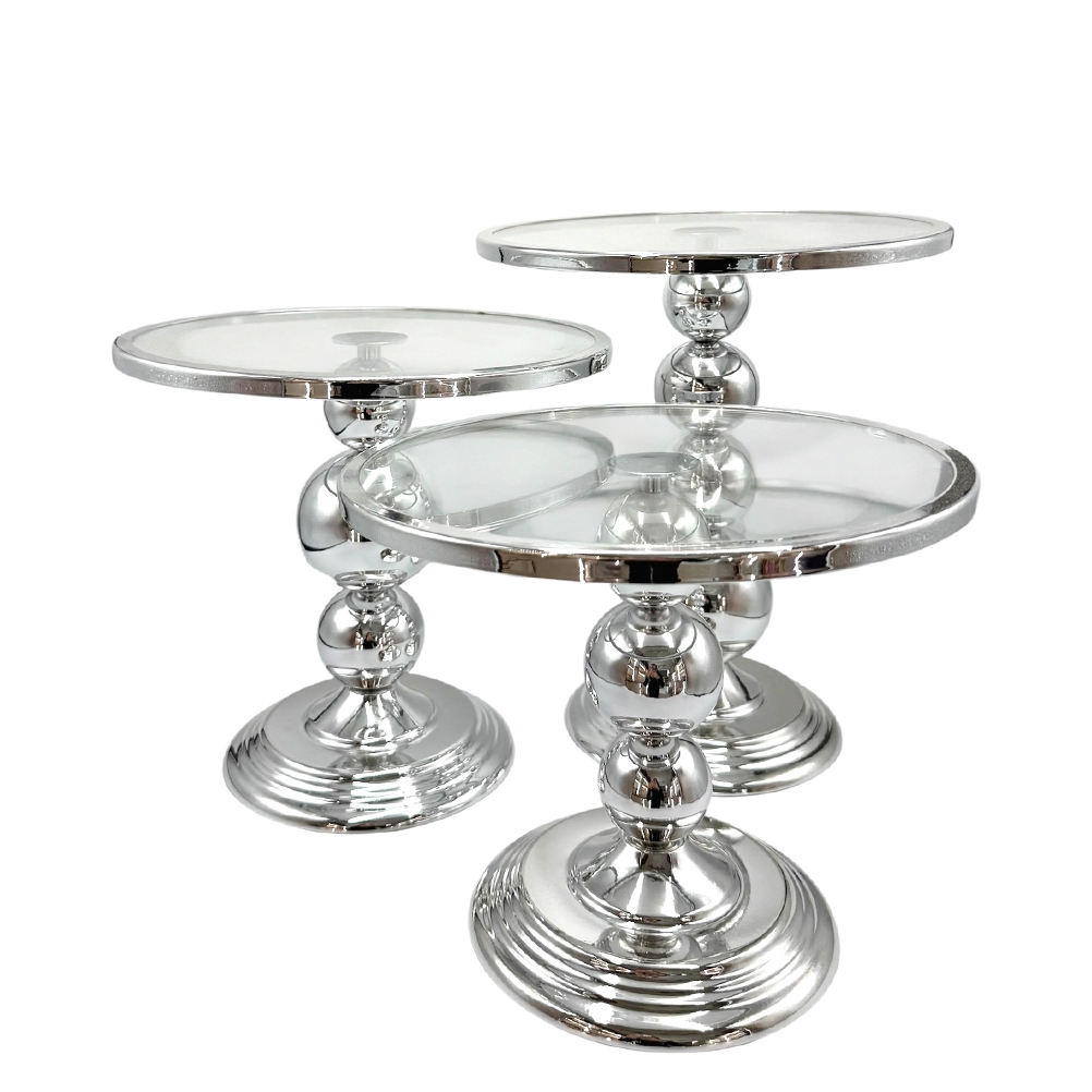 A69B540E-6F8D-87BC-C4F5-019D90A09A34_21 | La Vie en Rose Set of three chrome pedestal tables with glass tops in varying heights, forming a nesting arrangement in a modern style.