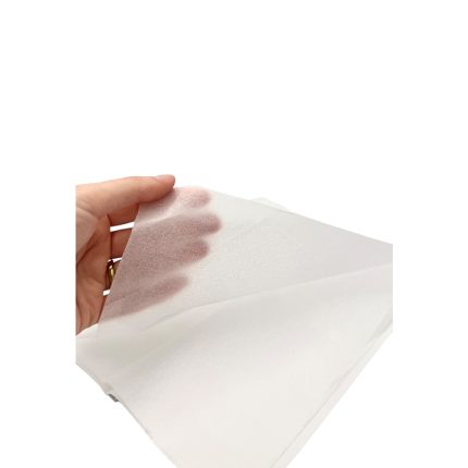 Hand lifting a white tissue with a brown stain against a plain white background.