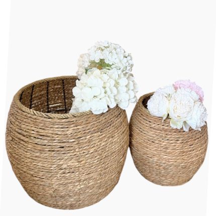 Two wicker baskets of different sizes filled with white hydrangea flowers, used as decorative planters.